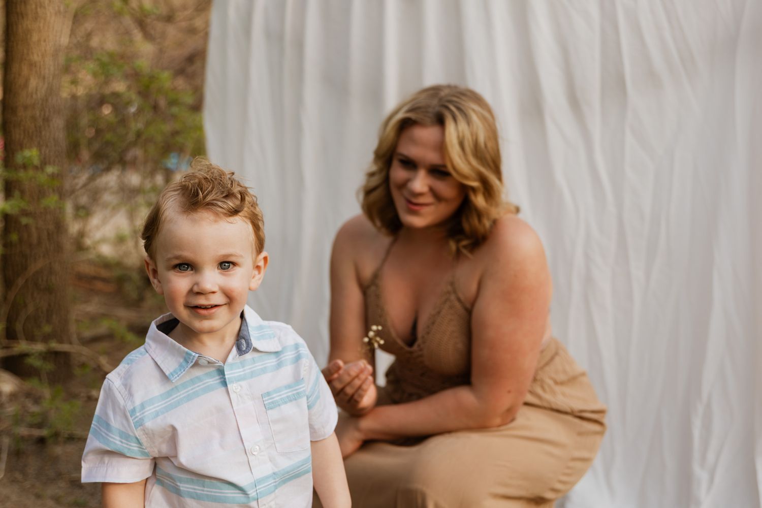A tender family portrait session with a brown dress and white backdrop in natural lighting.