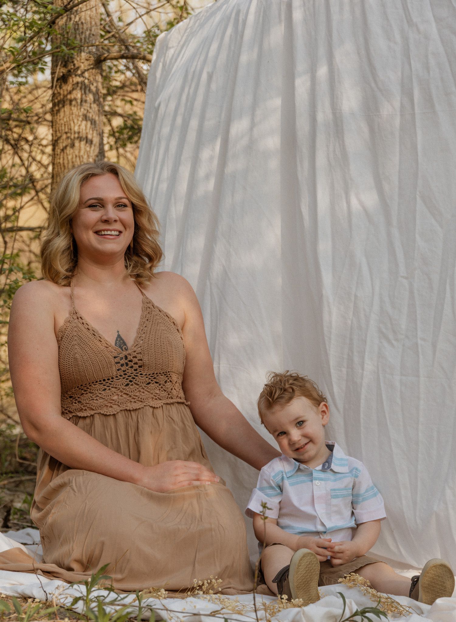 Relaxed outdoor family photography session featuring earth-toned clothing and white drapery.