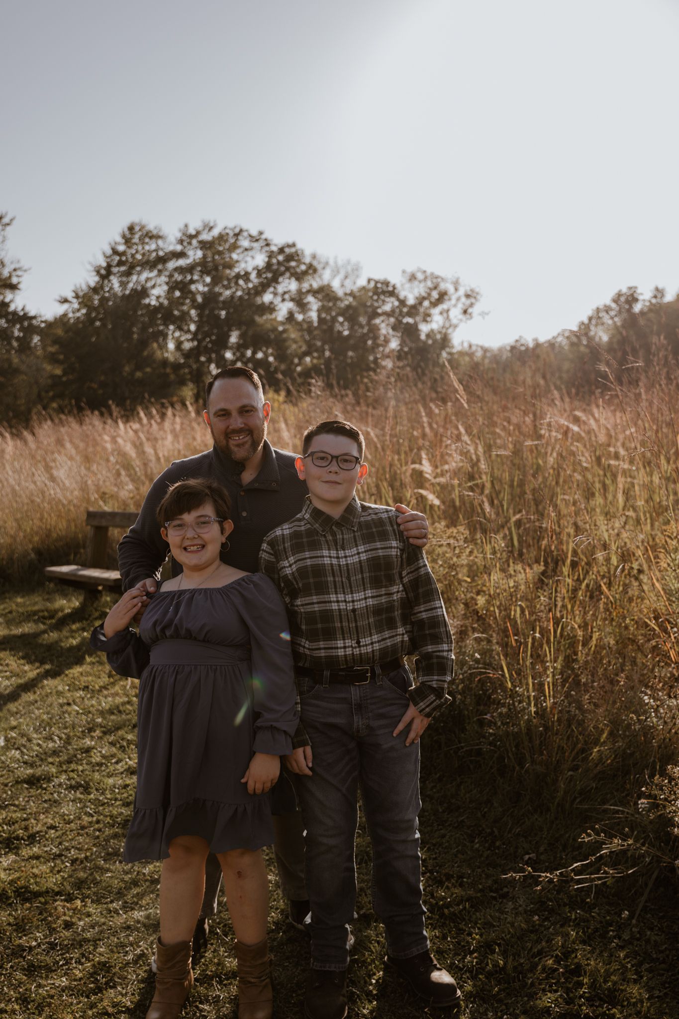 Two people share a candid moment while standing in a grassy field at dusk.