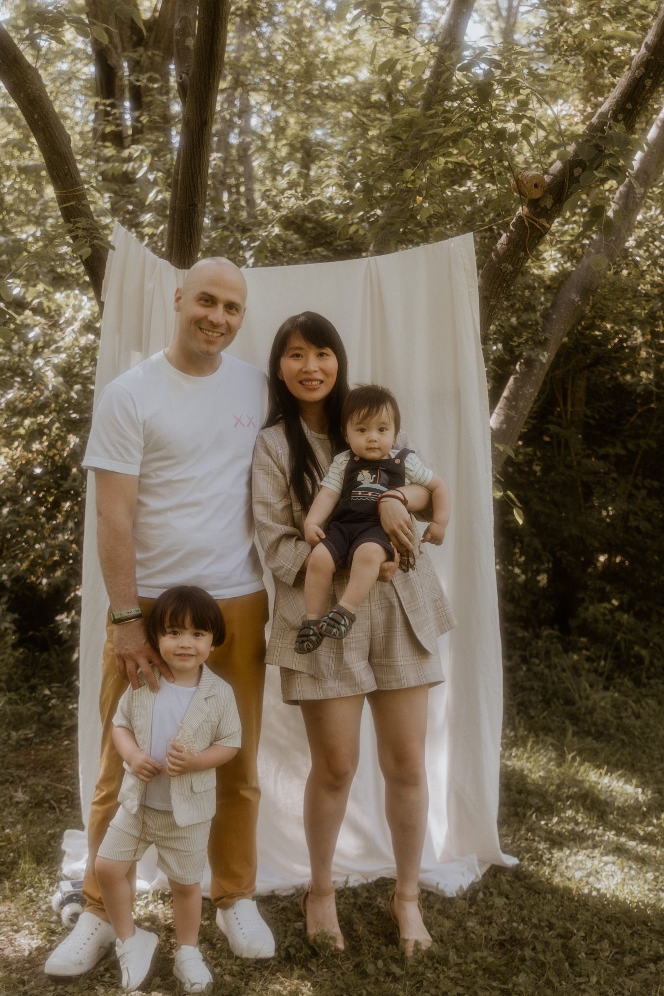 Casual outdoor family photoshoot with white backdrop and natural lighting.
