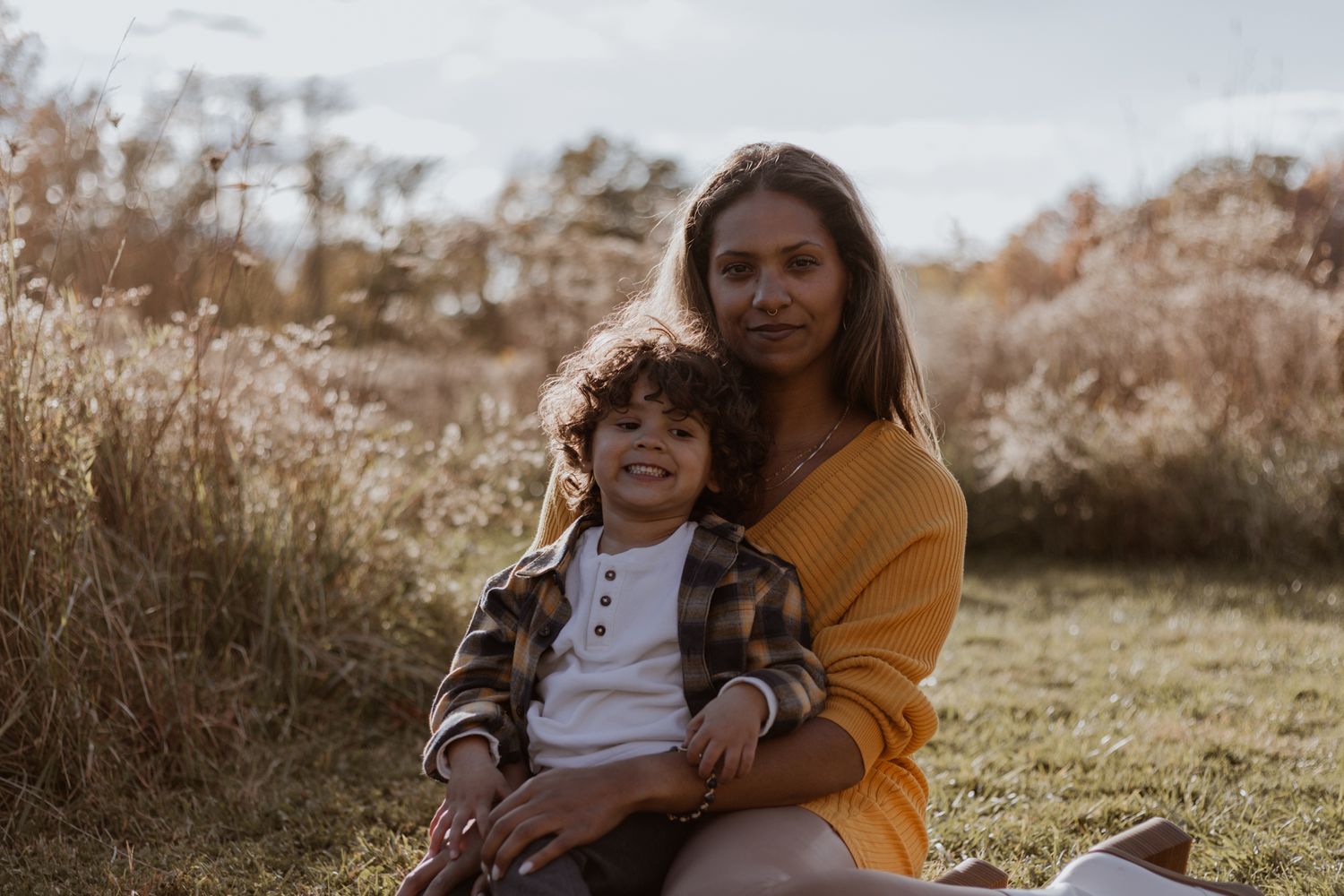 Mother and child share tender moments together in a sunlit outdoor setting.