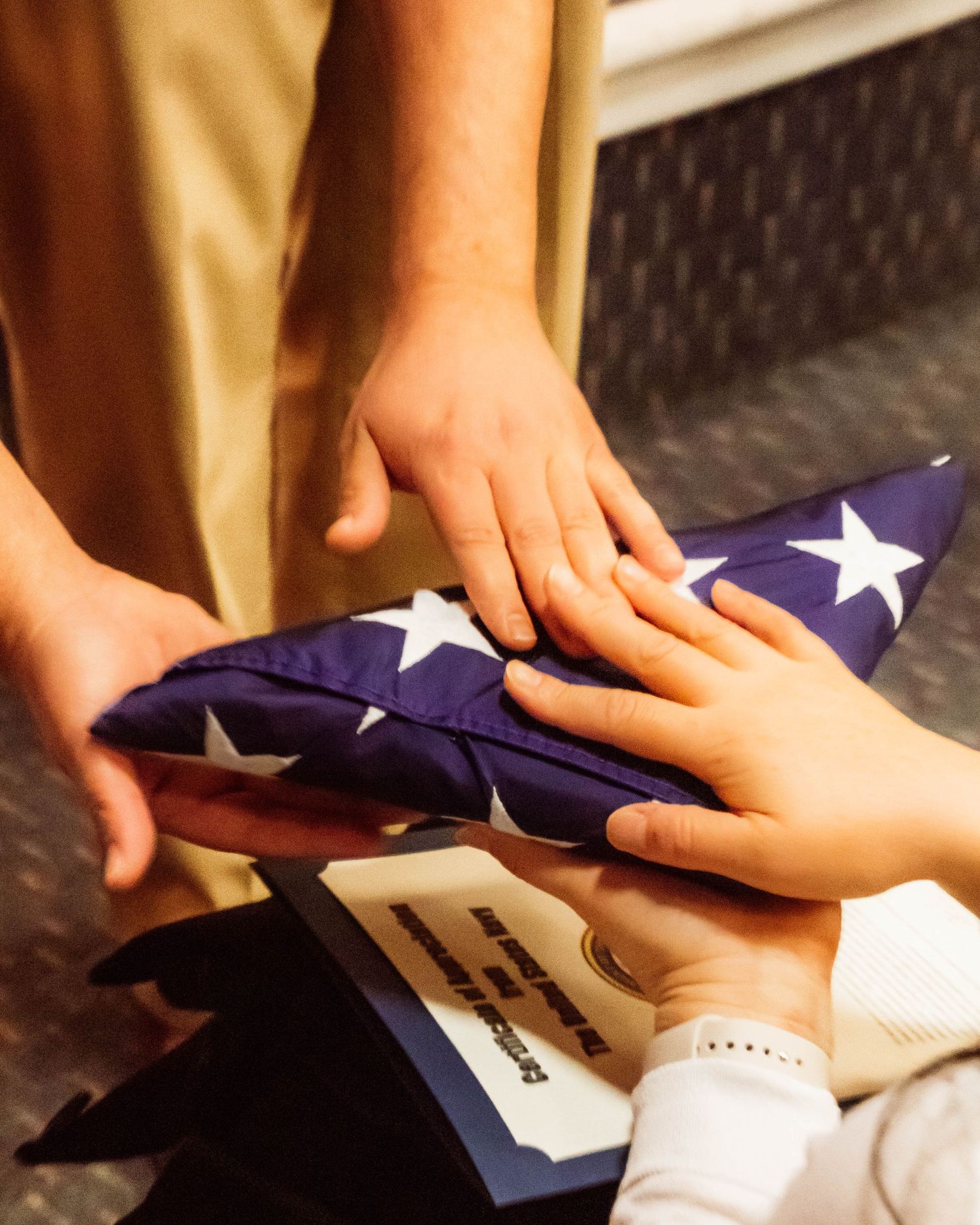 Close-up detail of a U.S. Navy service member in Khakis presenting a folded 'Old Glory' to a family member
