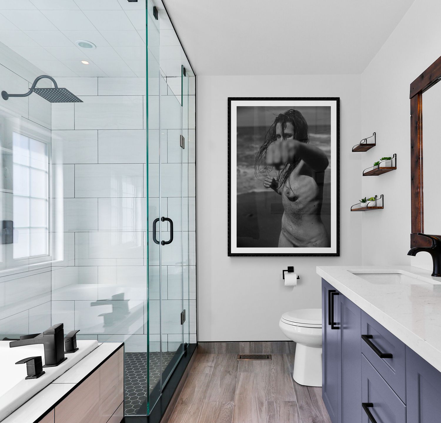 Modern bathroom with glass shower enclosure, white subway tile, floating vanity in navy blue, and wood-look flooring.