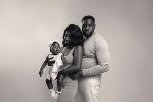 Family poses together in black and white studio portrait wearing light colored outfits.