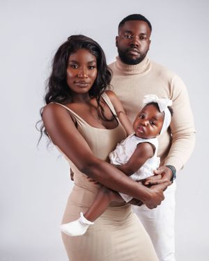 Family wearing coordinated neutral colors poses together in studio setting.