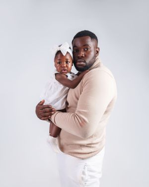 Parent and child in matching beige and white outfits pose for studio portrait.