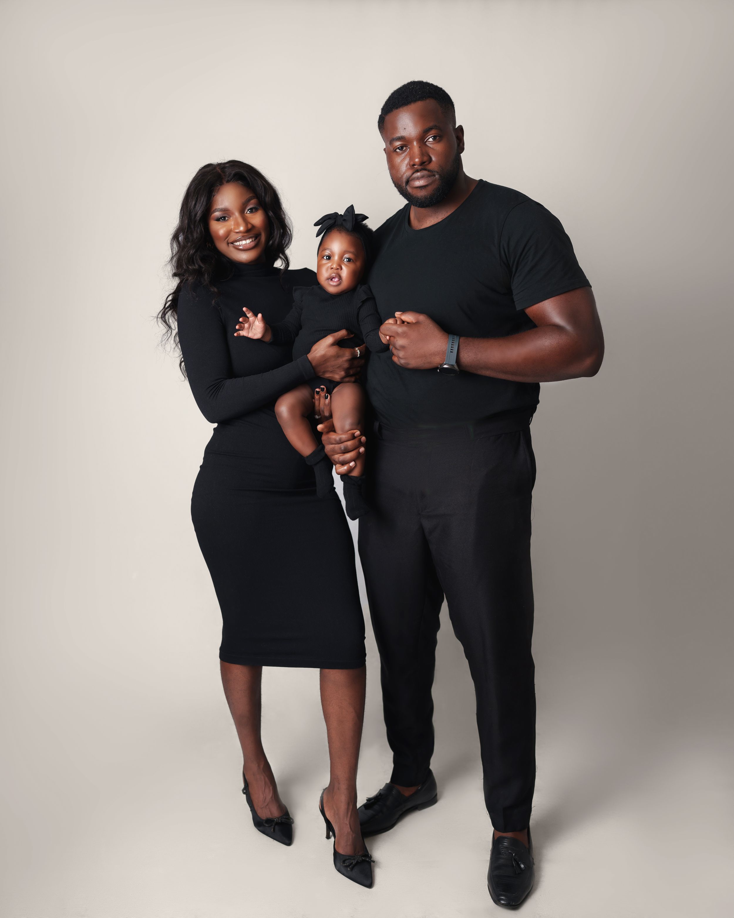 A formal family portrait with all members dressed in black against a light backdrop.