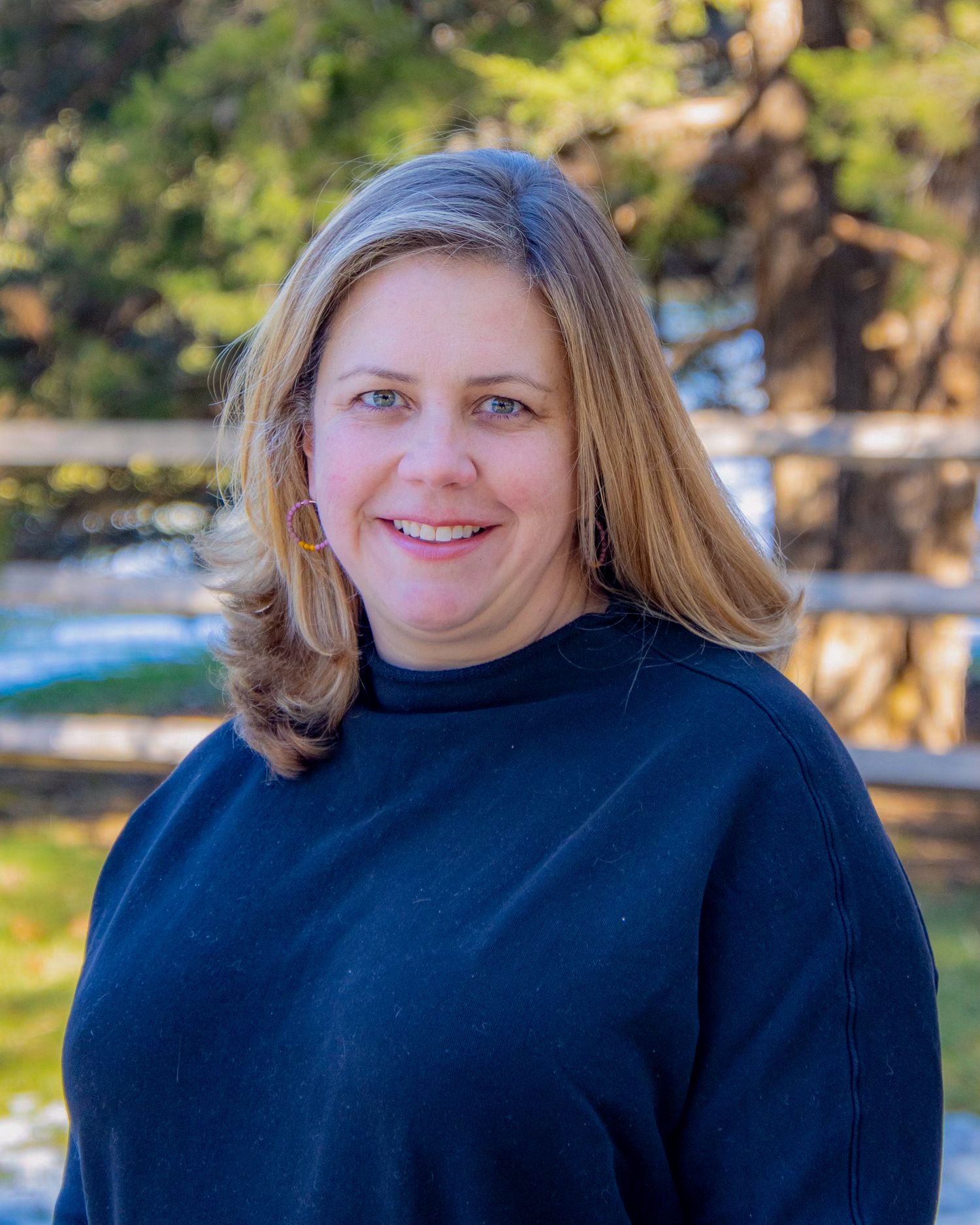 A woman poses during an outdoor headshot photography session in Sudbury, MA in a beautiful, natural setting.