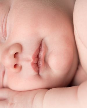 Close up macro shot of a sleeping baby's nose and facial features in soft lighting.