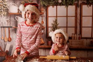 A cozy winter scene with people in matching red and white Nordic jammies baking holiday treats in a rustic kitchen.