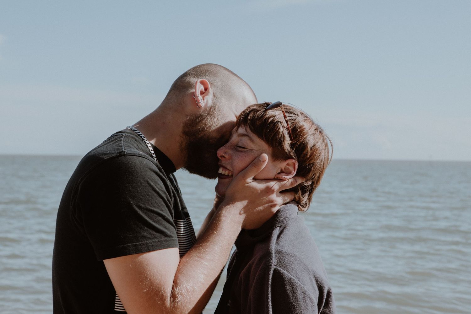 A romantic couple sharing an intimate kiss by the ocean.