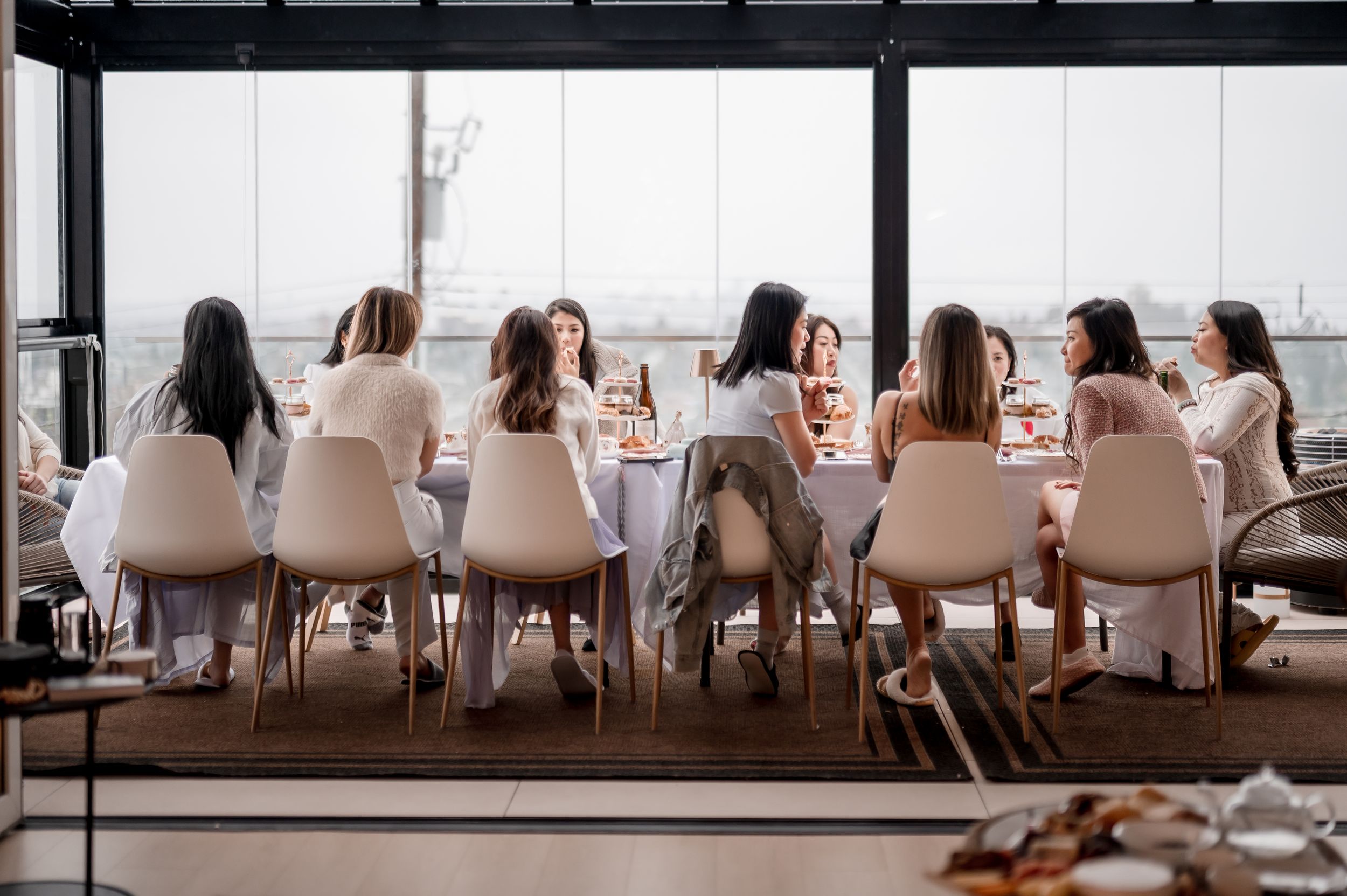 People seated in white modern chairs at a long table in a bright minimalist office space during a meeting.