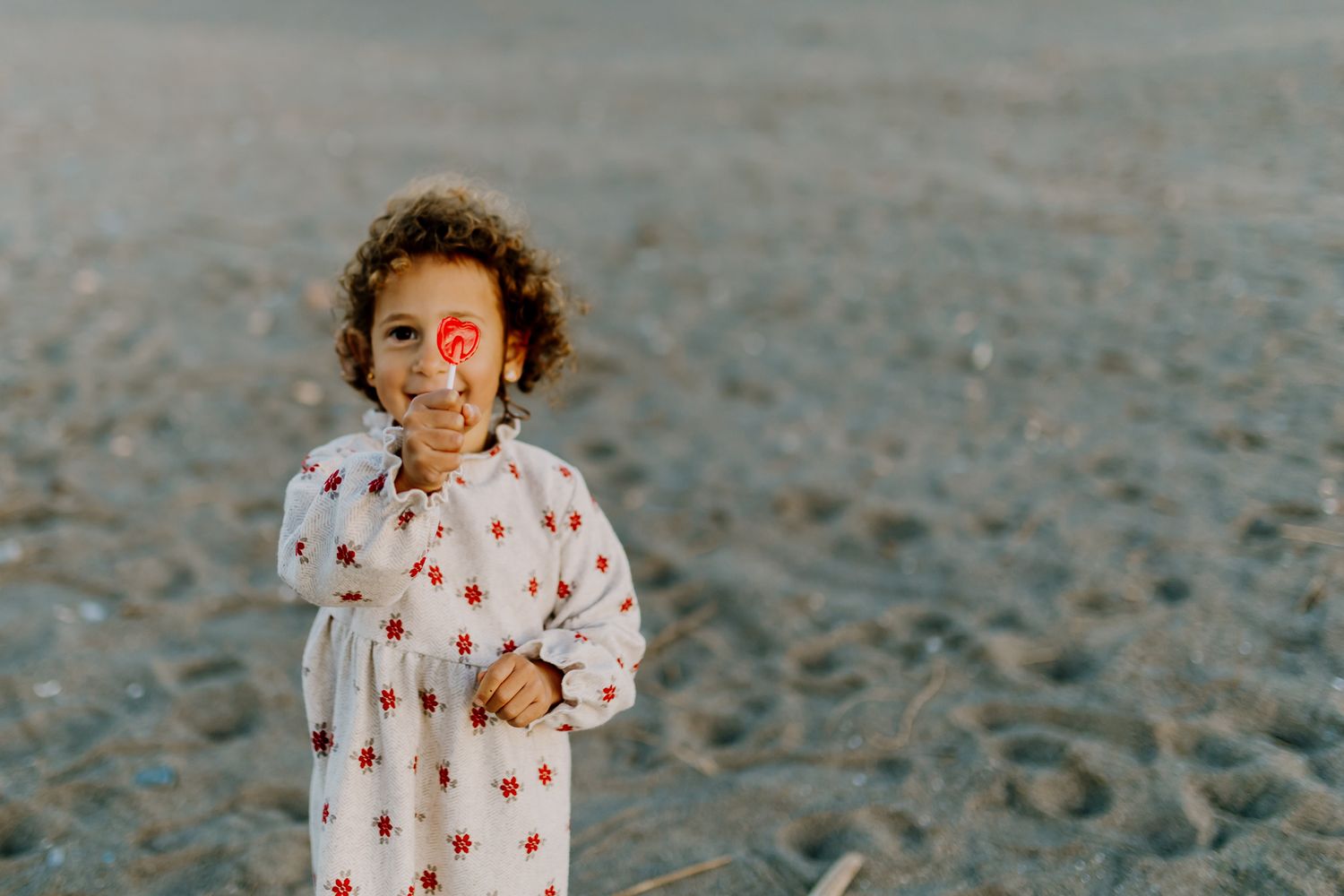Little Romi cover her eye with a red lollypop