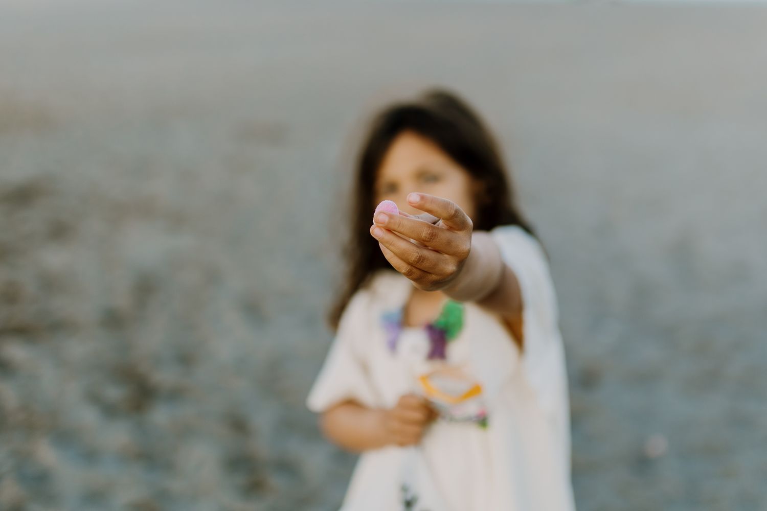 Girl is showing a small flower to the camera.