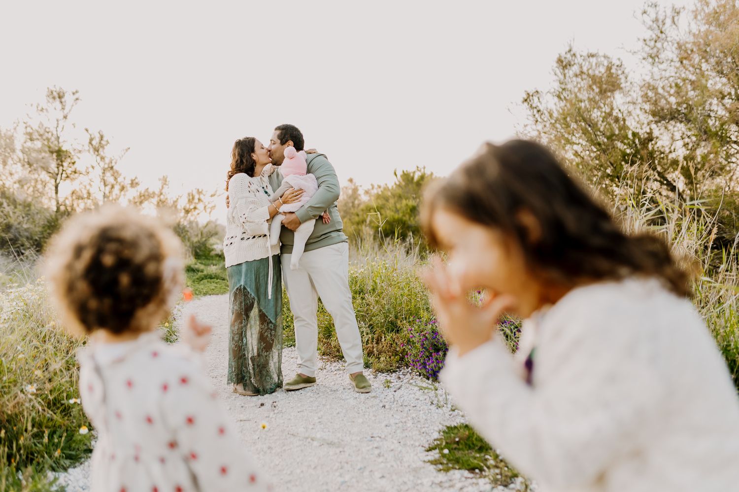 Mommy and daddy kissing while the two girls in the front showing like a surprise.