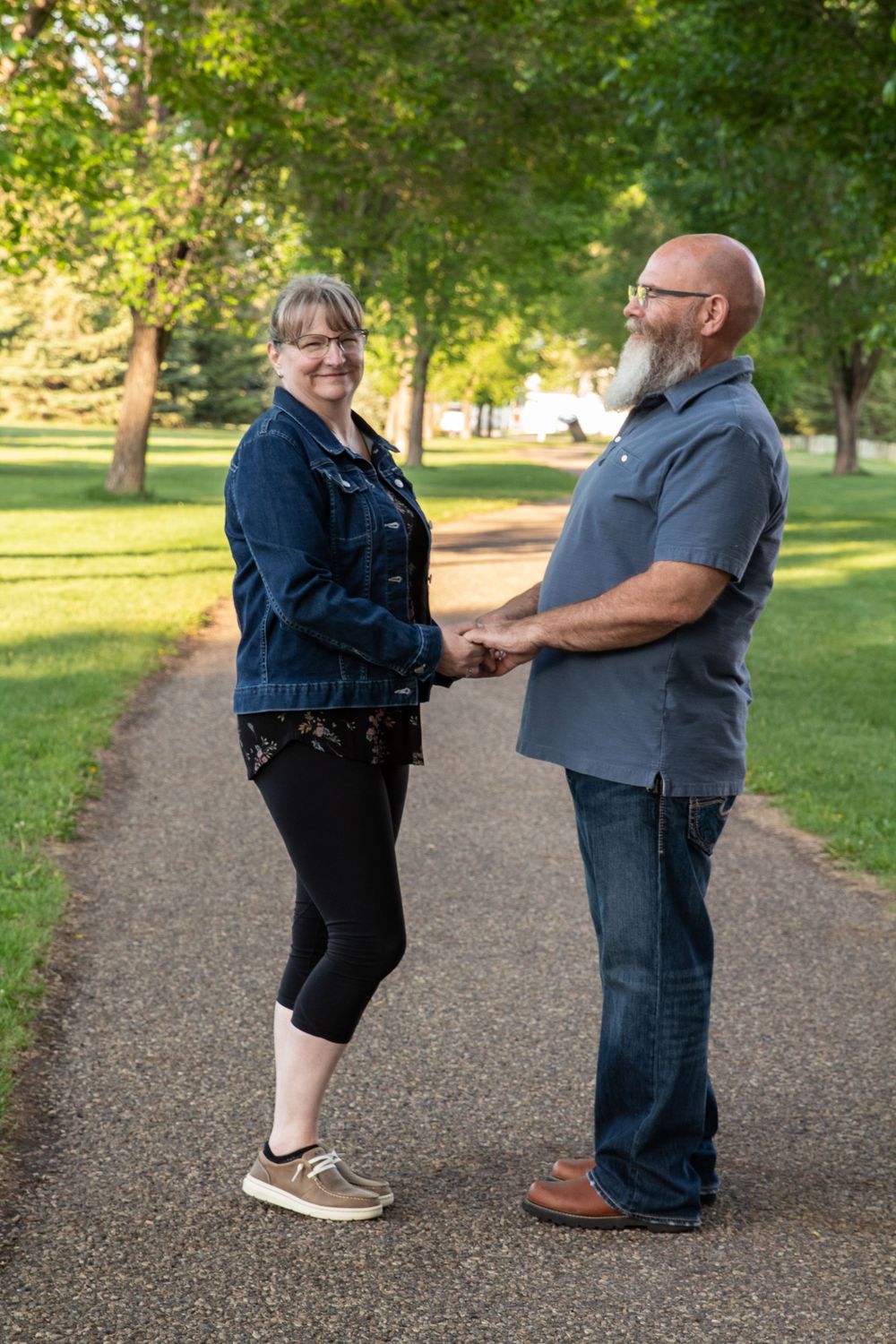 a couple stands together with trees in the background.