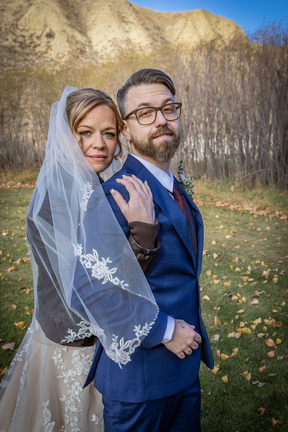 a bride in a leather jacket hugs her groom.