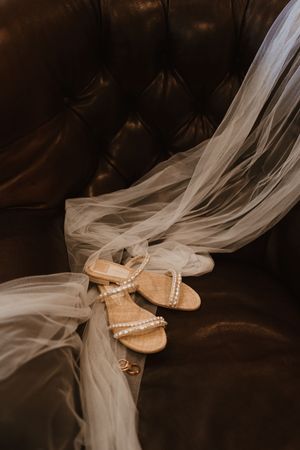Pearl-embellished bridal sandals with flowing veil on dark background.