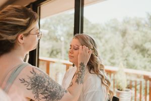 Wedding preparation scene showing makeup application in a sunlit room.