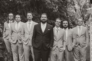 Groomsmen in light beige suits pose for a formal group photo outdoors.