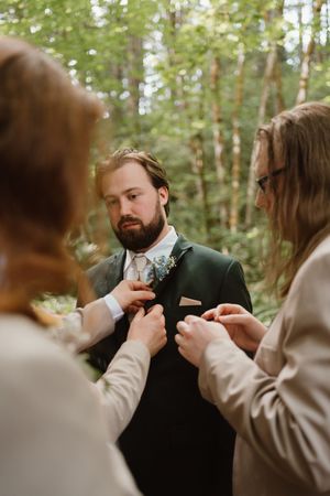 Groomsmen help adjust the groom's boutonniere before the ceremony.