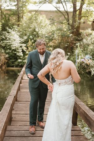 A couple shares a special moment on a wooden bridge over a pond.