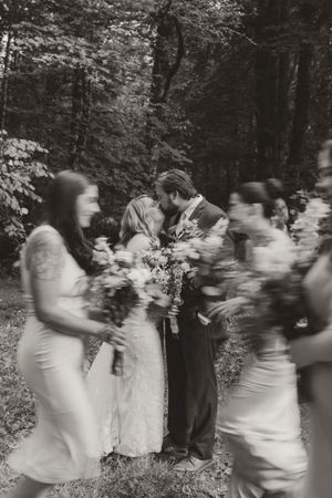 Black and white motion blur photo of wedding party celebrating in the woods.