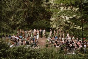 Wide angle view of wedding guests gathered for an intimate forest ceremony.