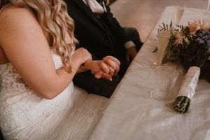 Close-up details of wedding attire and floral arrangements on a light surface.