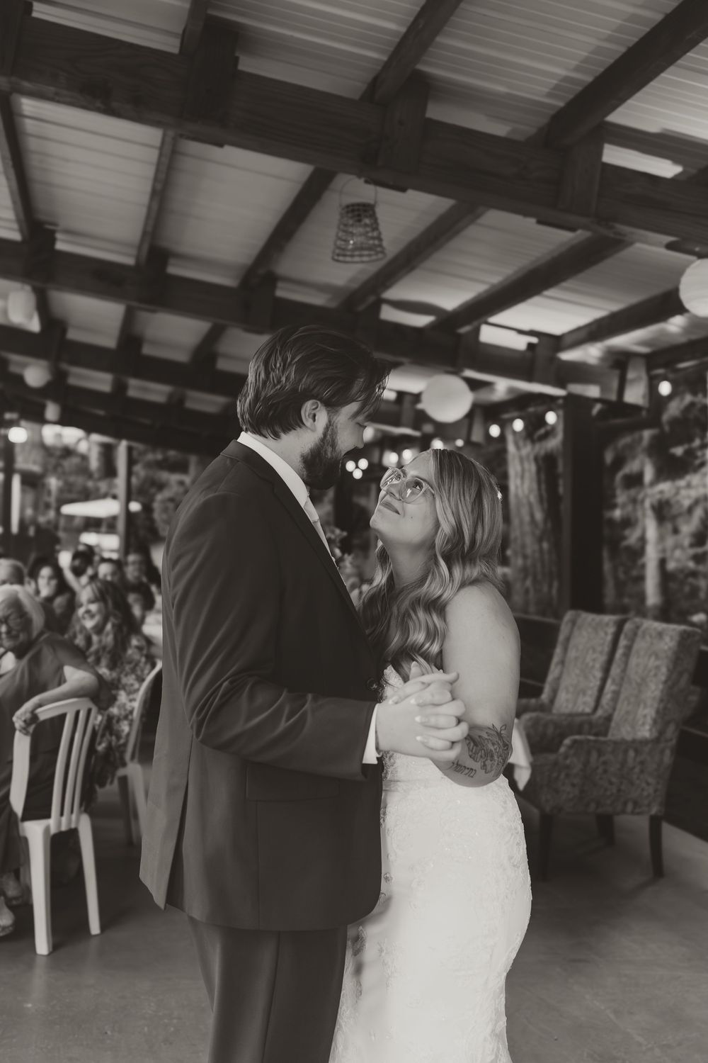 Black and white photos capture newlyweds dancing intimately at their rustic reception venue.