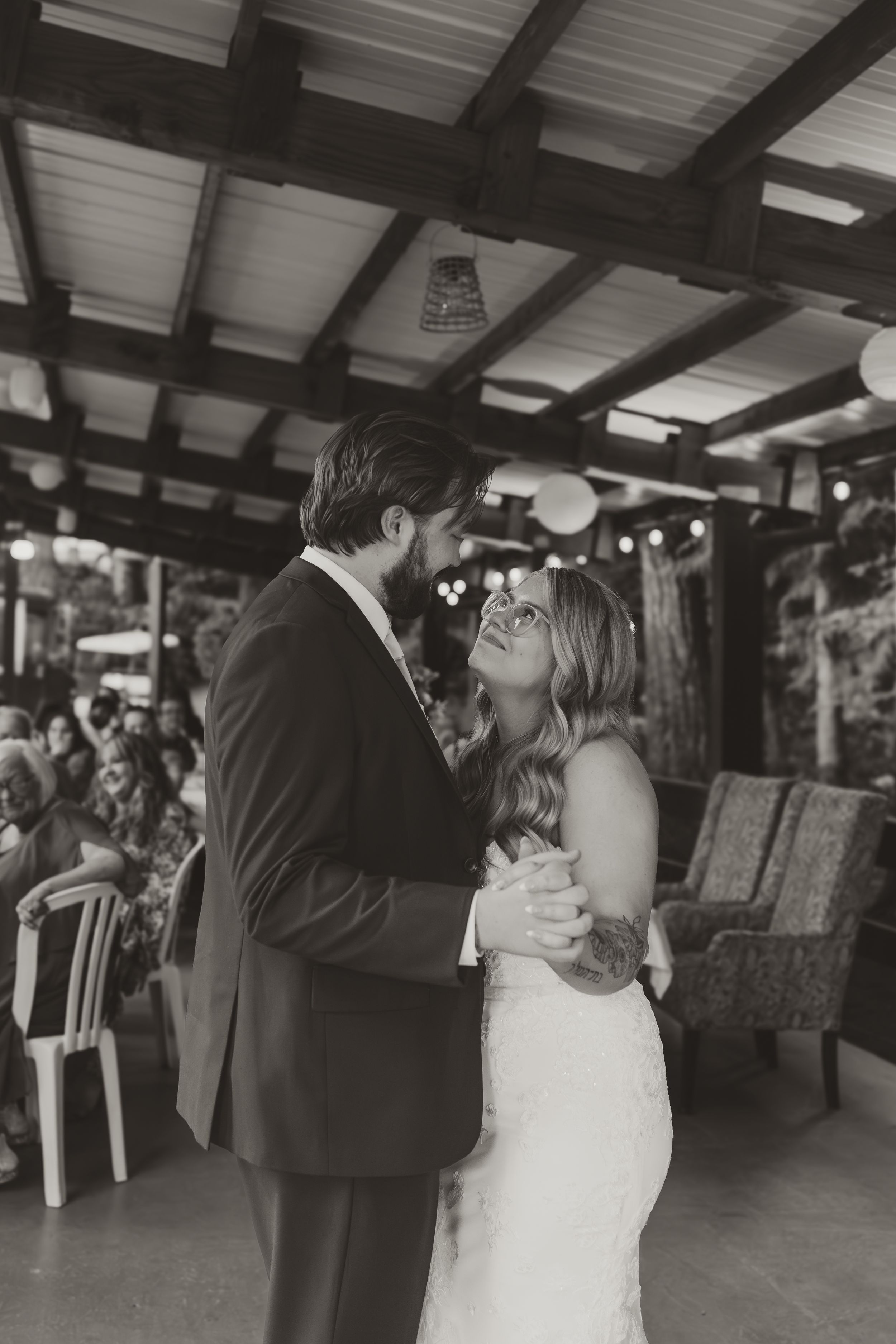 Black and white photos capture newlyweds dancing intimately at their rustic reception venue.