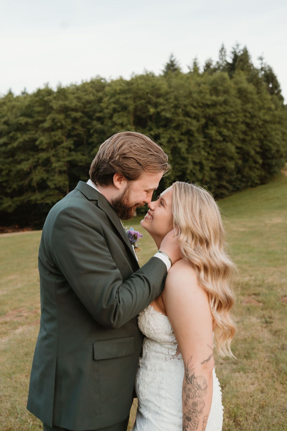 An intimate moment between newlyweds in a scenic meadow setting.