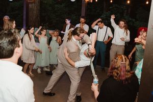 Wedding reception dance party with string lights and guests celebrating.