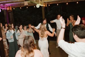 Lively dance floor scene at wedding reception with guests dancing under string lights.
