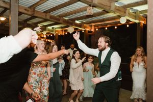 Wedding reception dance party with guests enjoying themselves under rustic pavilion.