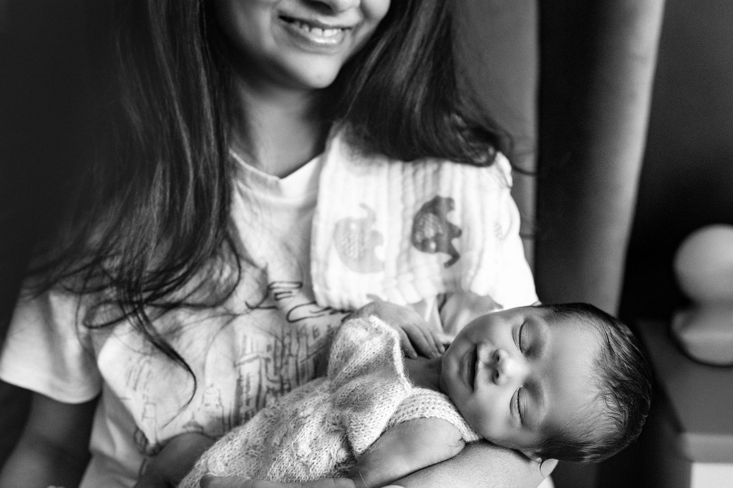 Black and white photo showing a tender moment between a caregiver and a peaceful sleeping baby.