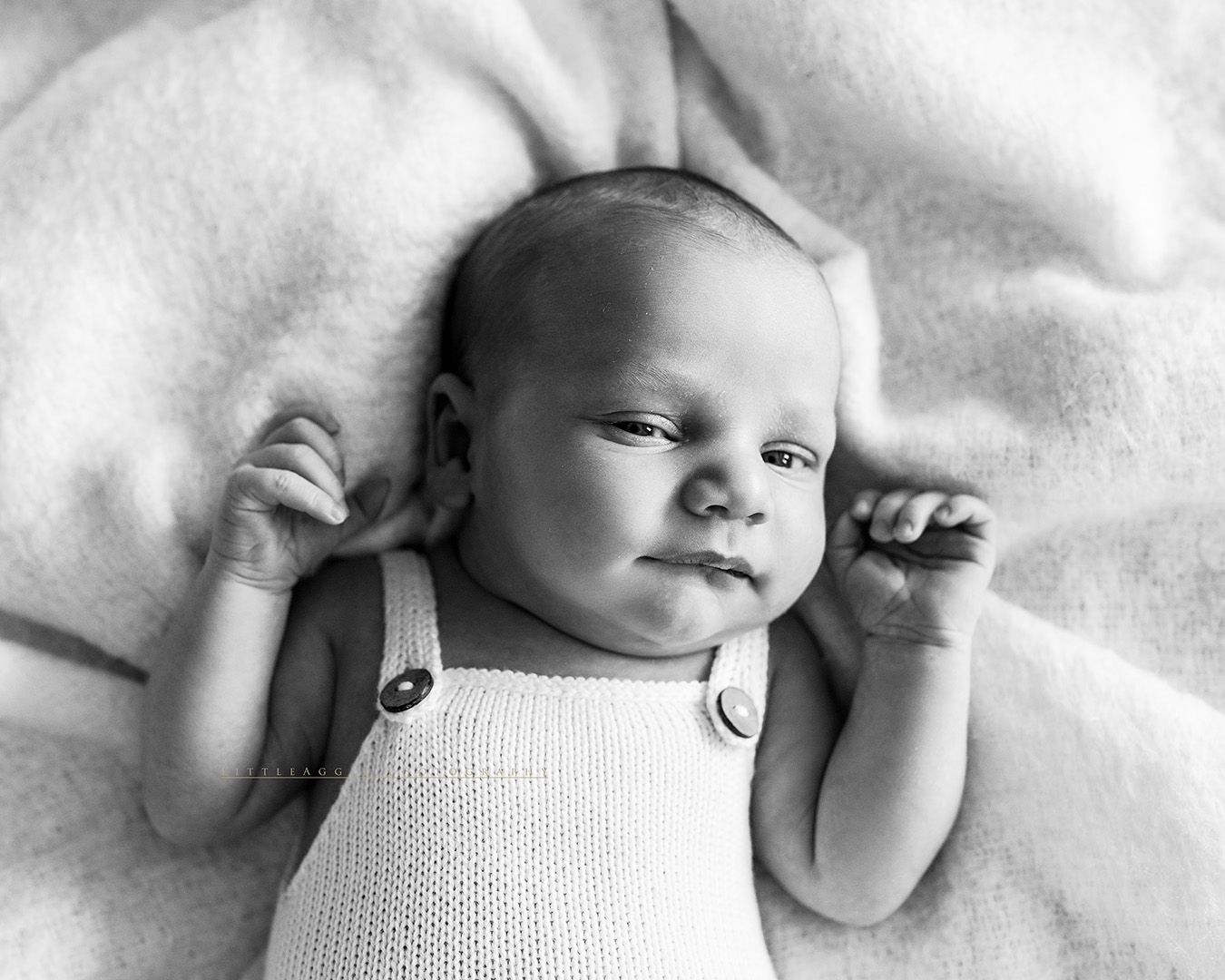A stylish black and white collage of a sleeping newborn baby wearing a knit onesie.