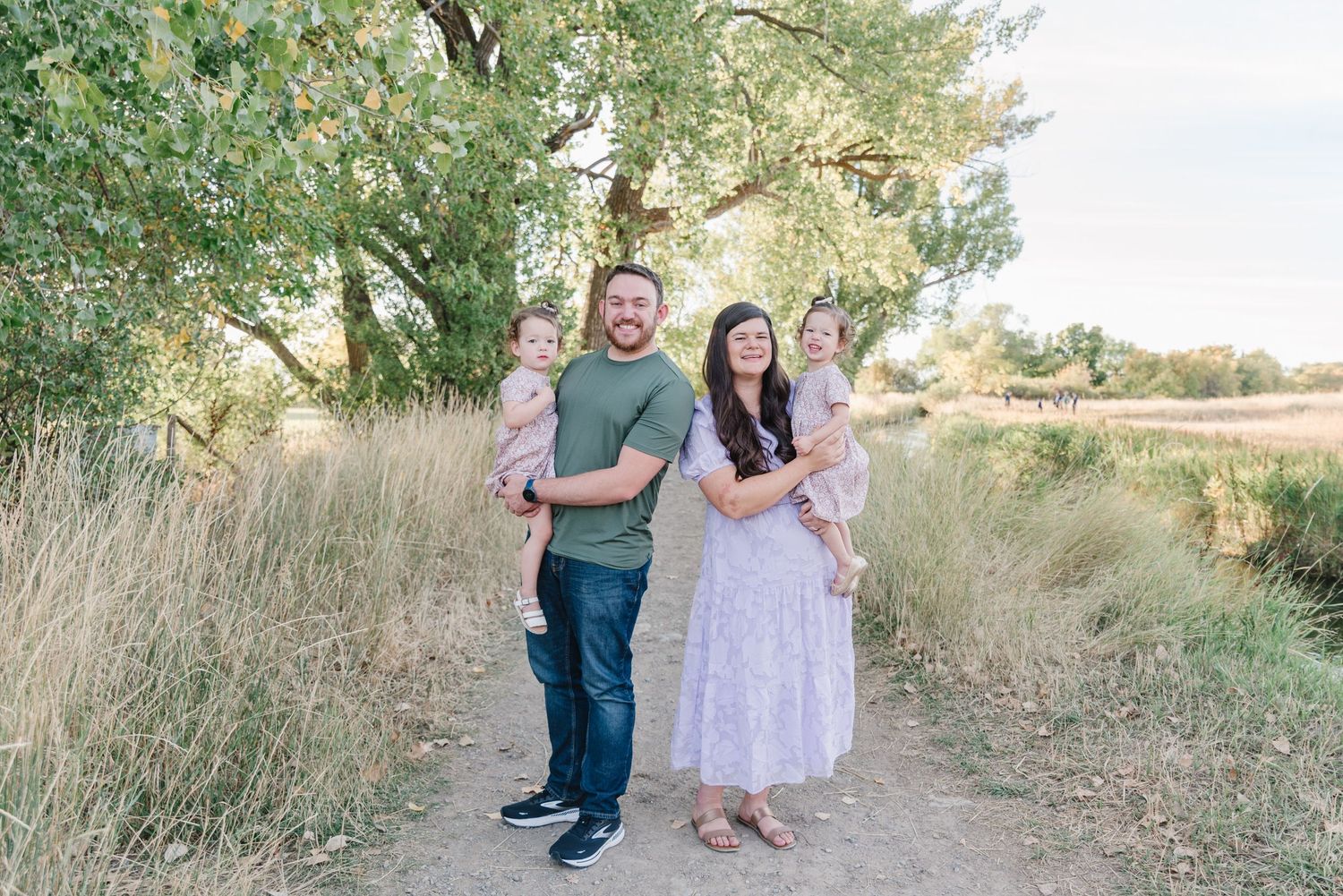 A family walks together through a scenic natural path during golden hour.