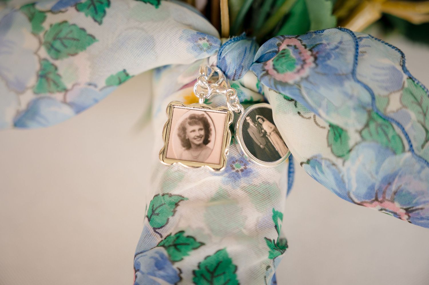A vintage photo charm with blue floral decor displayed against a delicate lace background.