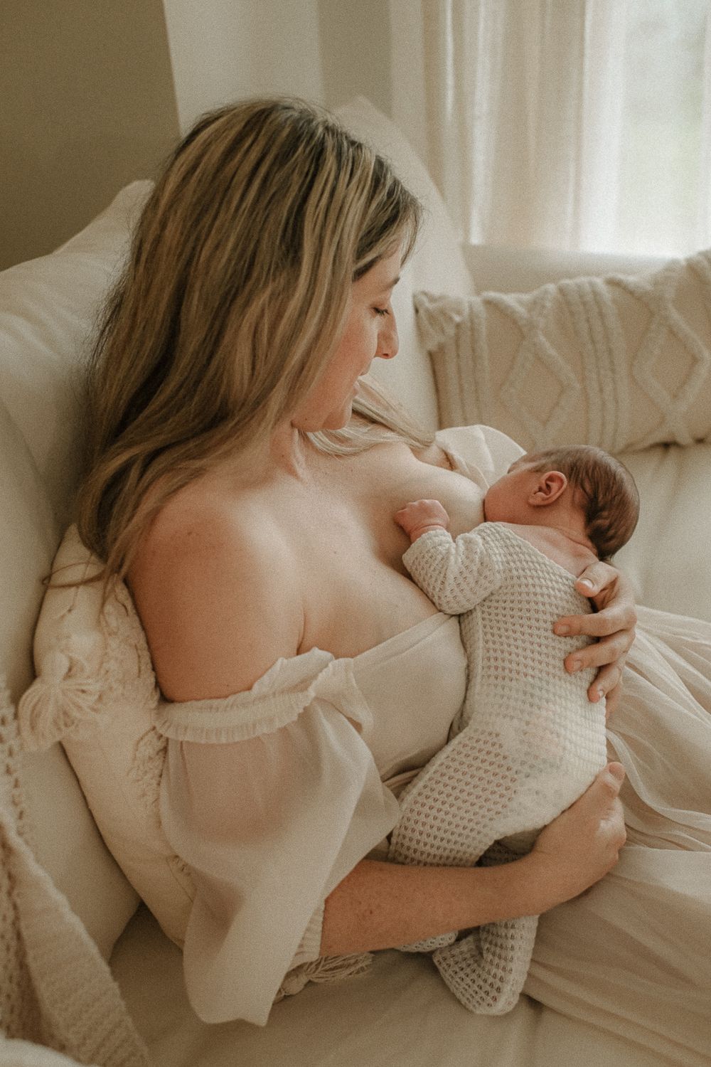 An intimate bonding moment between mother and newborn in soft natural light.