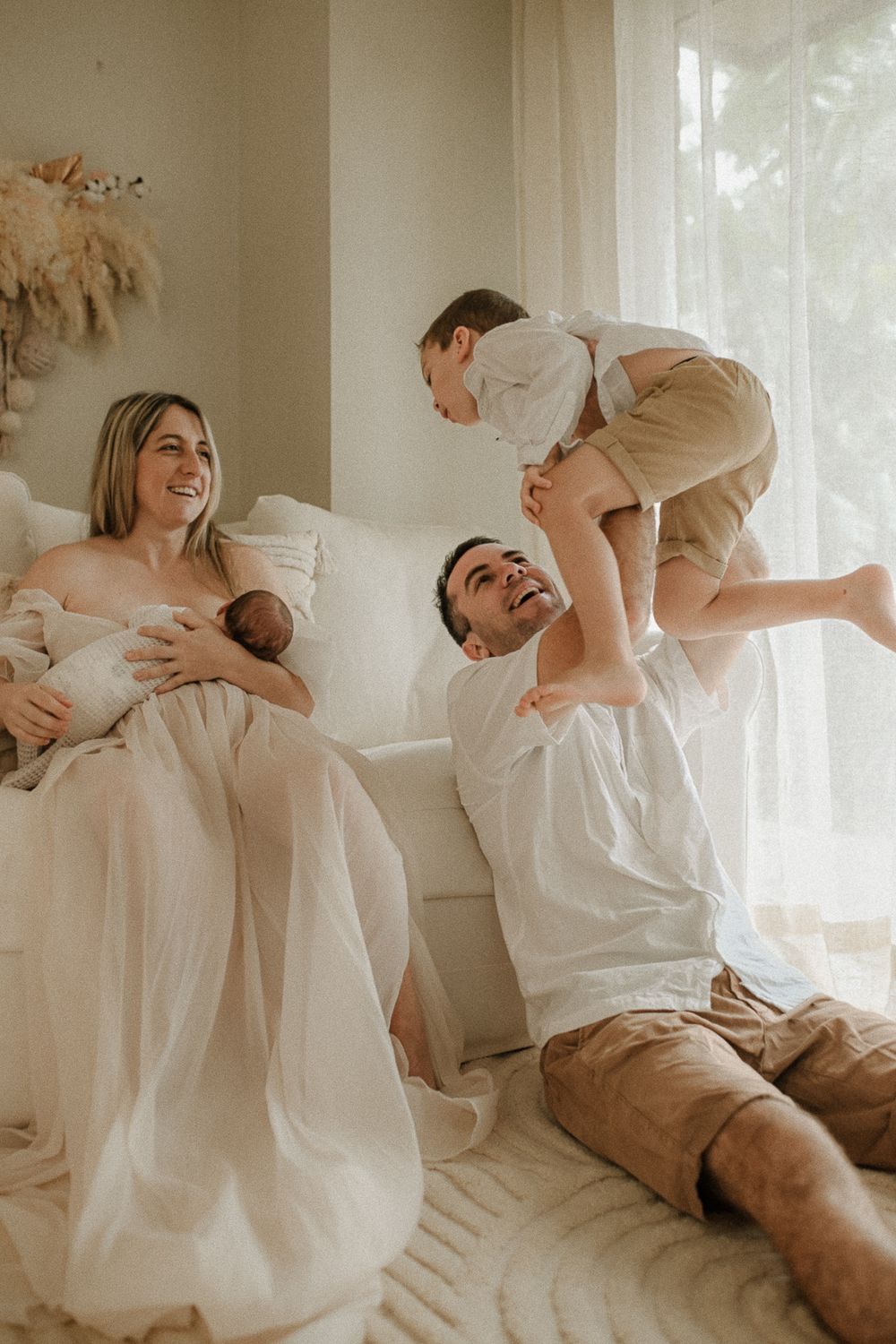 A playful family moment captured in a bright, airy room with white decor.
