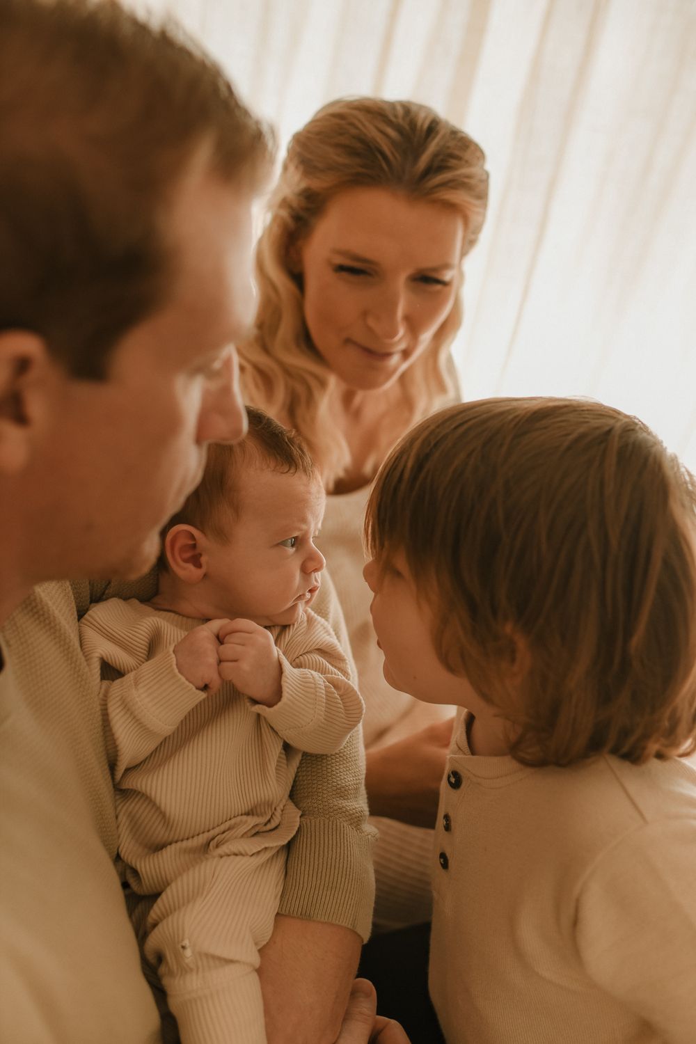 Intimate family moment with a baby in neutral colored clothing and soft lighting.