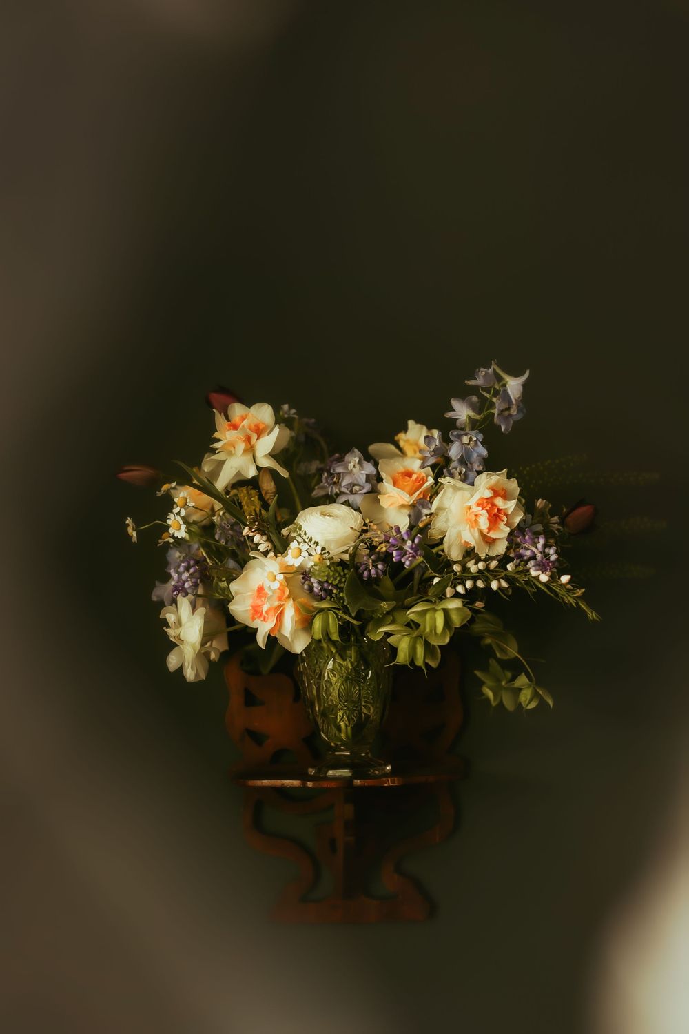 Elegant flower arrangement with peach roses and greenery in a glass vase.