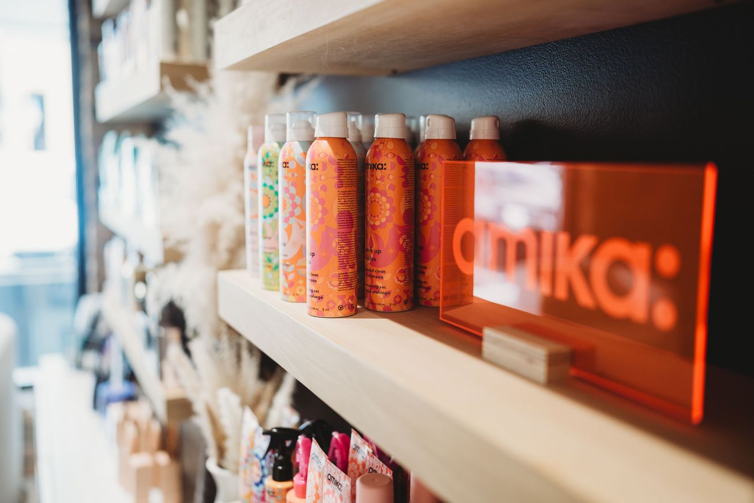 Colorful hair product bottles displayed on wooden salon retail shelves.