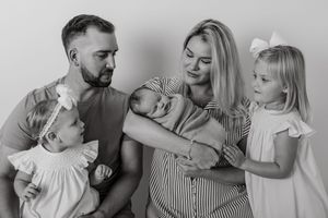 Family of three sharing playful moments in black and white portrait series.