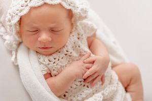 Newborn baby sleeping peacefully wrapped in delicate white lace.
