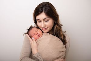 A tender moment captured in soft beige tones showing a loving embrace against a light background.