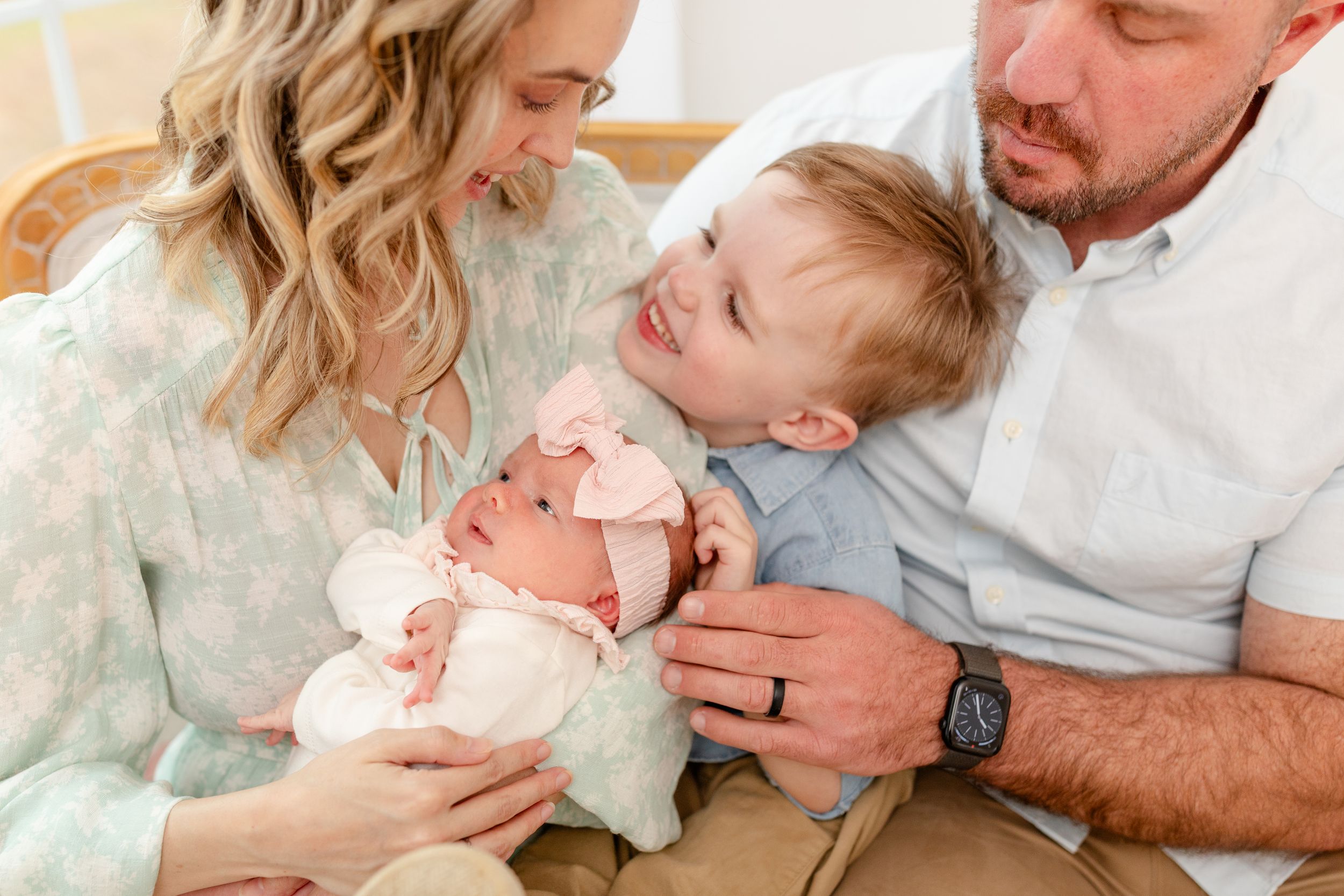 A family shares a tender moment together while holding a newborn baby wearing white.