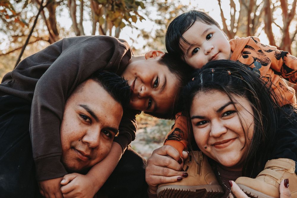 A close-up shot of a family group huddled together outdoors in autumn.