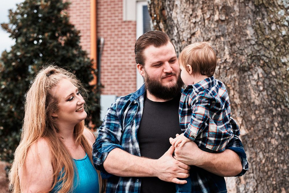 Family shares a joyful moment together outdoors by a brick building.